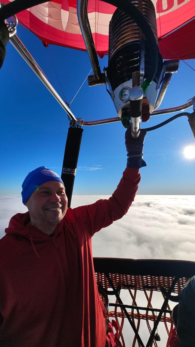 Pilot balonu ponad chmurami — uśmiechnięty, spokojny